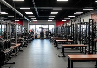 Strength training zone with weight racks, benches, and resistance machines at PrimaFit